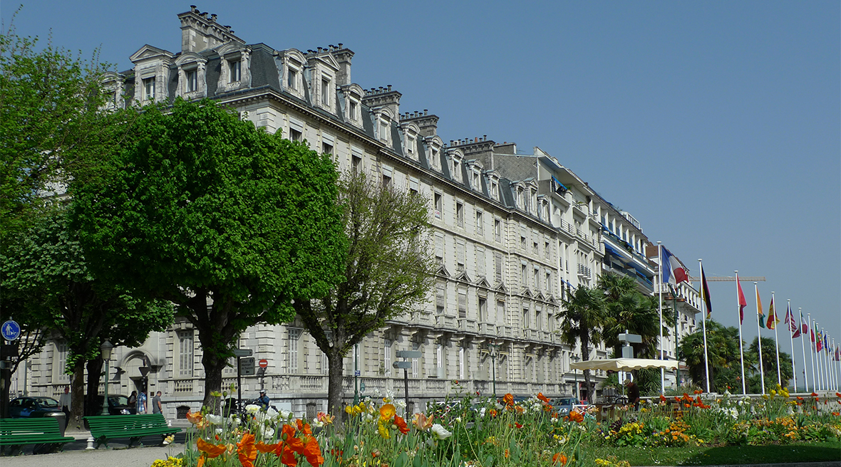 Boulevard des Pyrénées with blooming flowers in the foreground with European Flags and the Chateau de Pau in the background